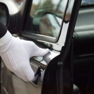 A gloved hand opening a car door handle.