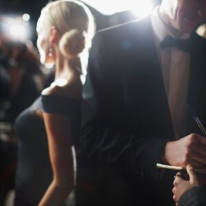 A woman in an elegant black dress and a man in a tuxedo at a formal event.