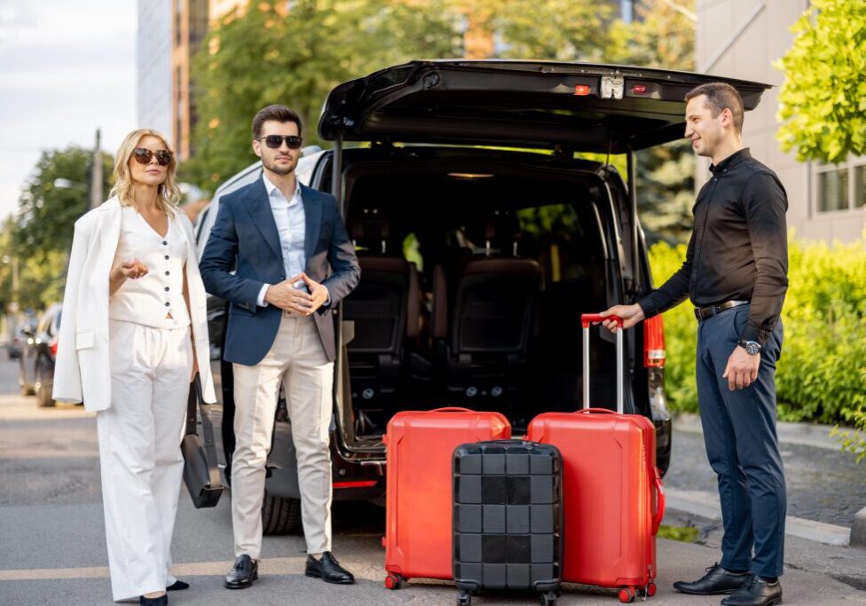 Three stylish travelers with red luggage near a black SUV in a sunny setting.